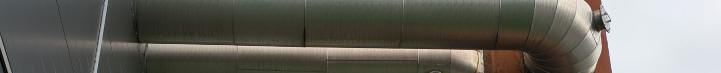 rør som går mellom et metallplatebygg og et rør med rustfarge