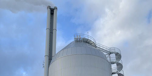 toppen av akkumulatortank. tanken er rund og belagt med stålplater, det går en spiraltrapp opp til toppen. I bakgrunn vises pipe tilhørende forbrenningsanlegget på Tiller